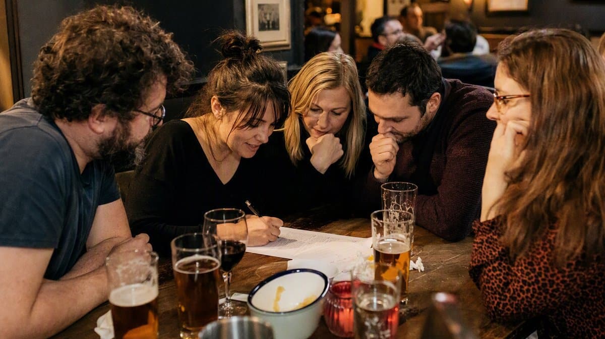 Coworkers filling in a paper answer sheet together at a pub trivia night